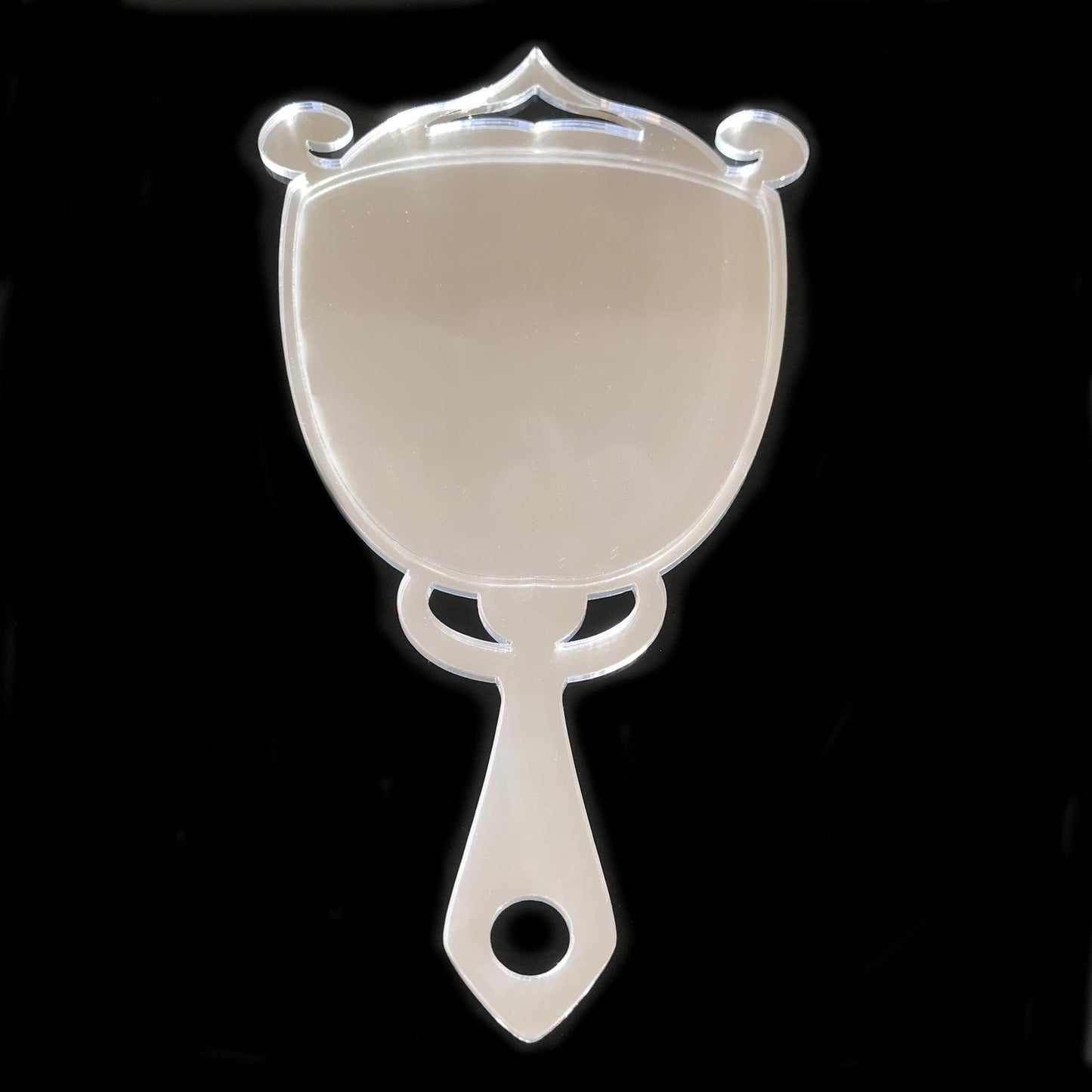Art Deco trophy-shaped acrylic hand mirror with ornate top scrolls and a handle featuring a circular cutout.
