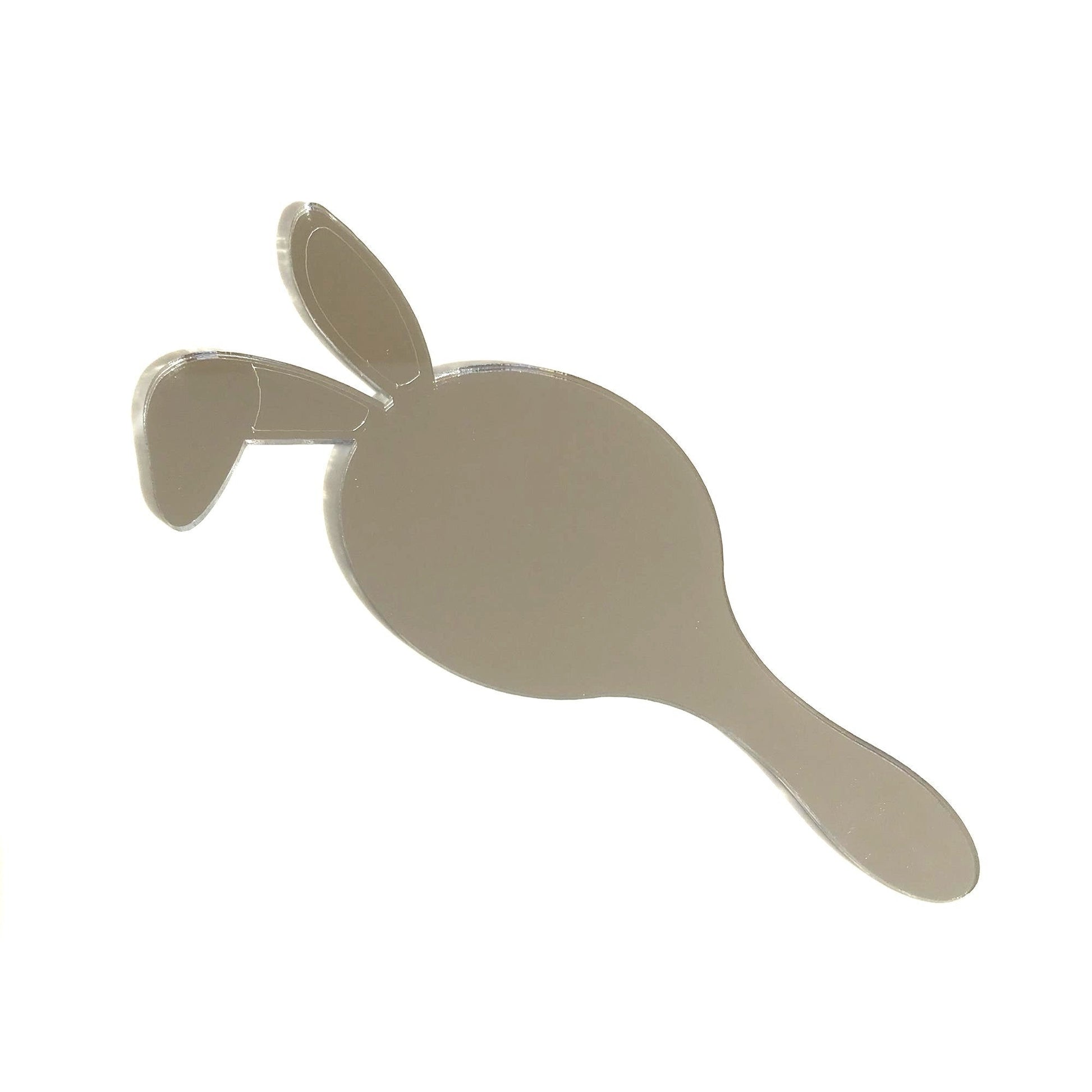 A silver mirrored hand-held mirror shaped like a bunny head with two upright ears and a handle.