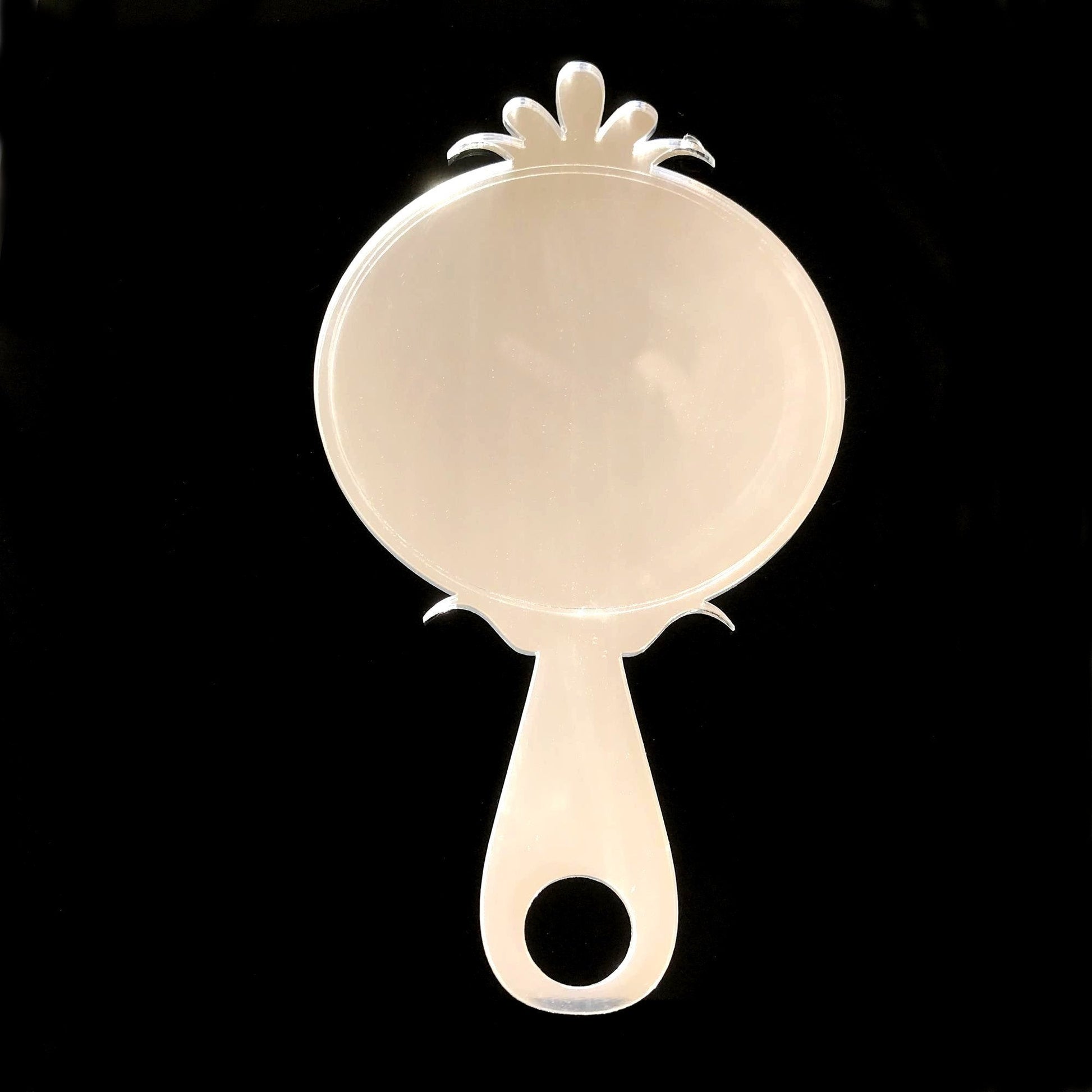 Clear acrylic round hand-held mirror with decorative top and handle cutout on black background.