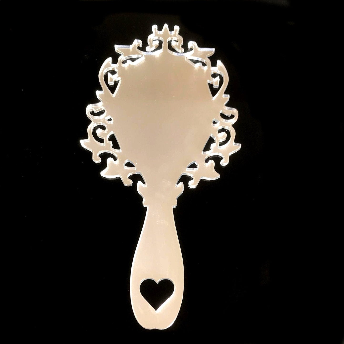 Victorian vintage style hand-held mirror with ornate, filigree frame and a heart cutout on the handle.