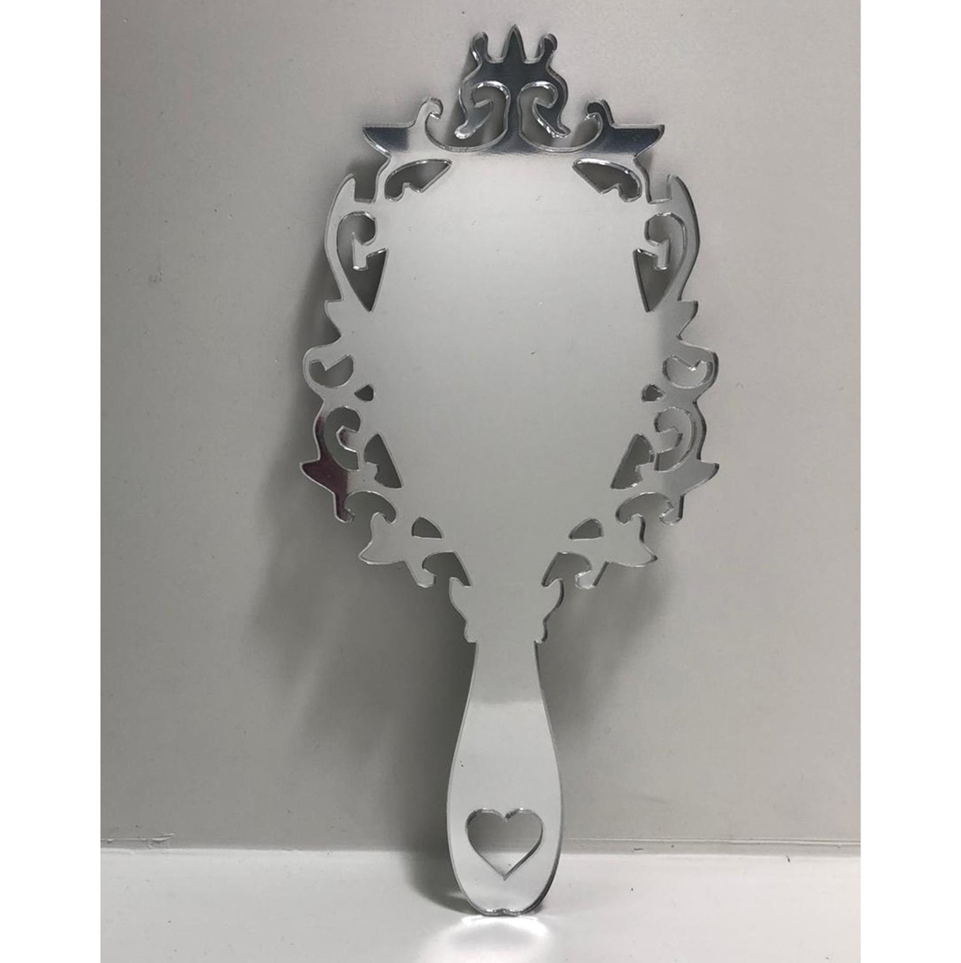 Victorian vintage-style silver hand-held mirror with ornate scrollwork frame and heart-shaped cutout on the handle.