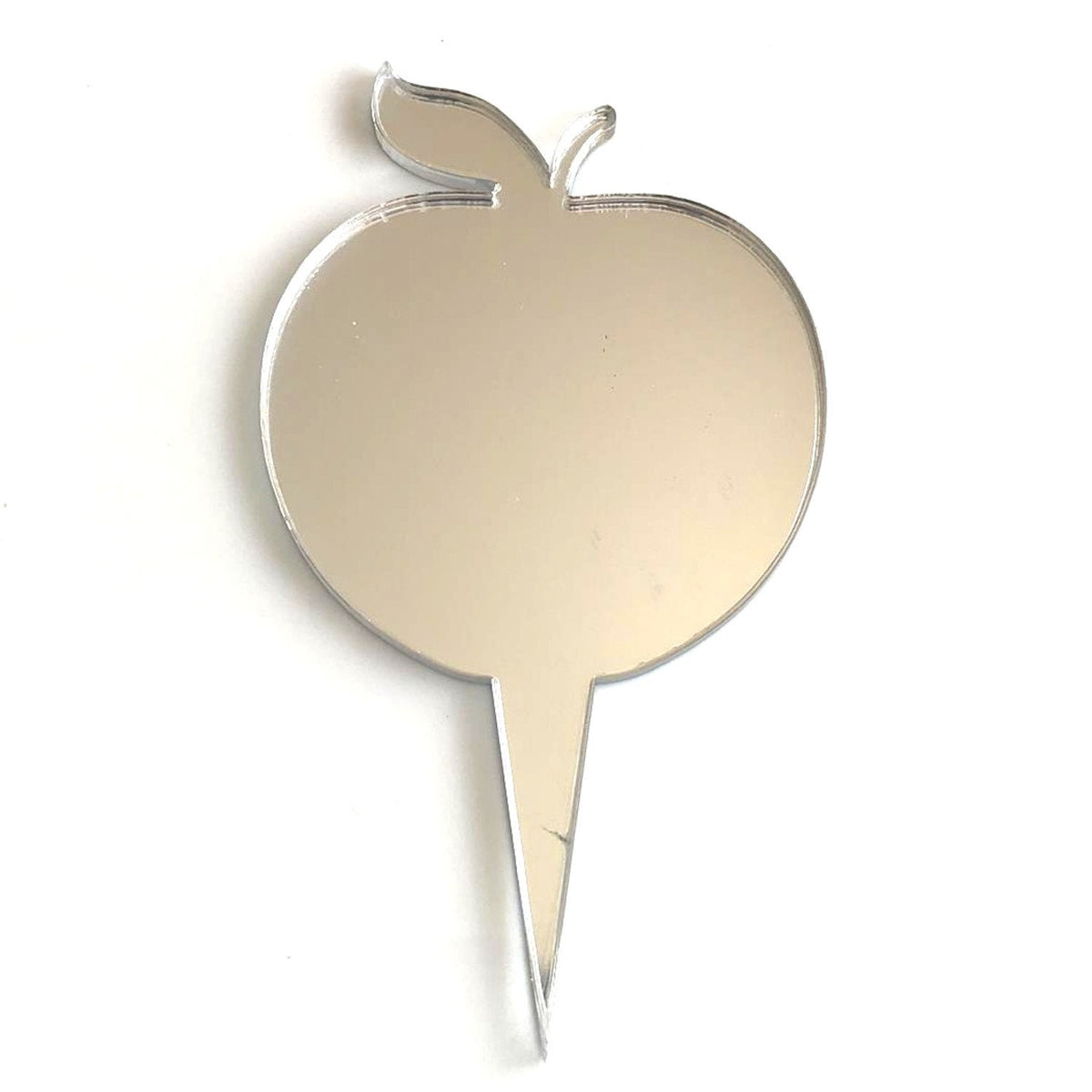 A reflective silver mirrored acrylic cake topper shaped like an apple with a pointed stake at the base.
