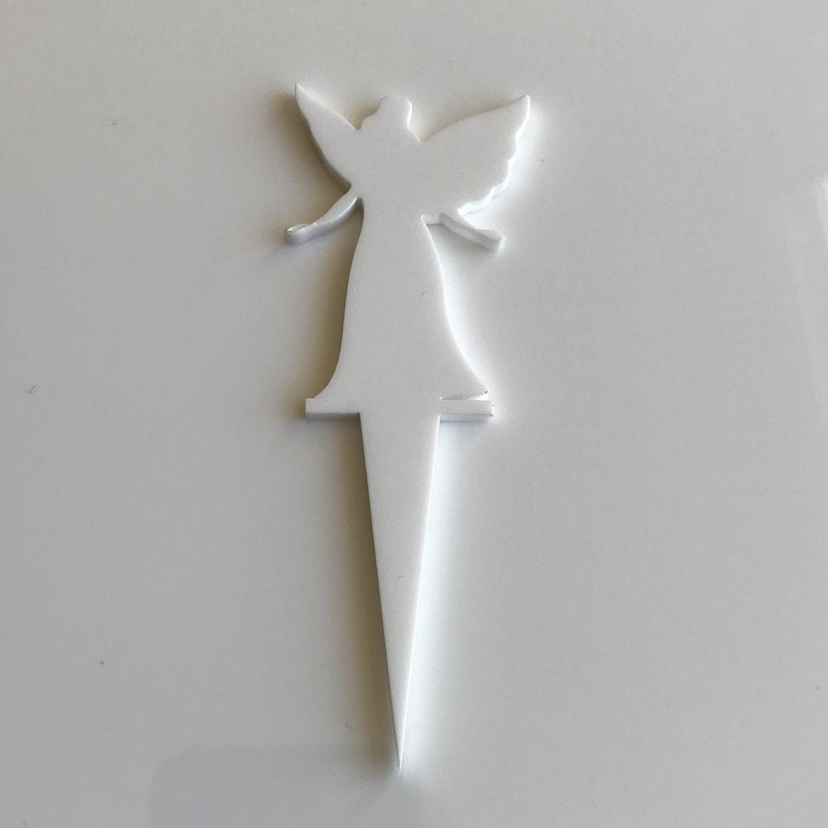 White acrylic fairy-shaped cake topper with a pointed stake for insertion.