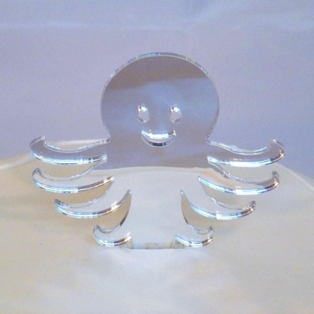 Clear recycled acrylic octopus cake topper with a smiling face and curved tentacles, set in a white cake.