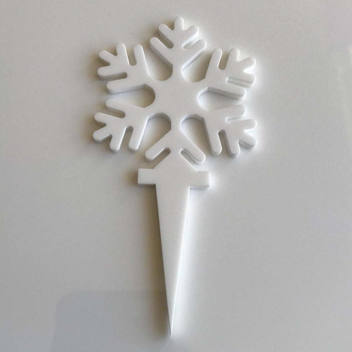 A matte white, recycled plastic snowflake cupcake topper on a plain white background.