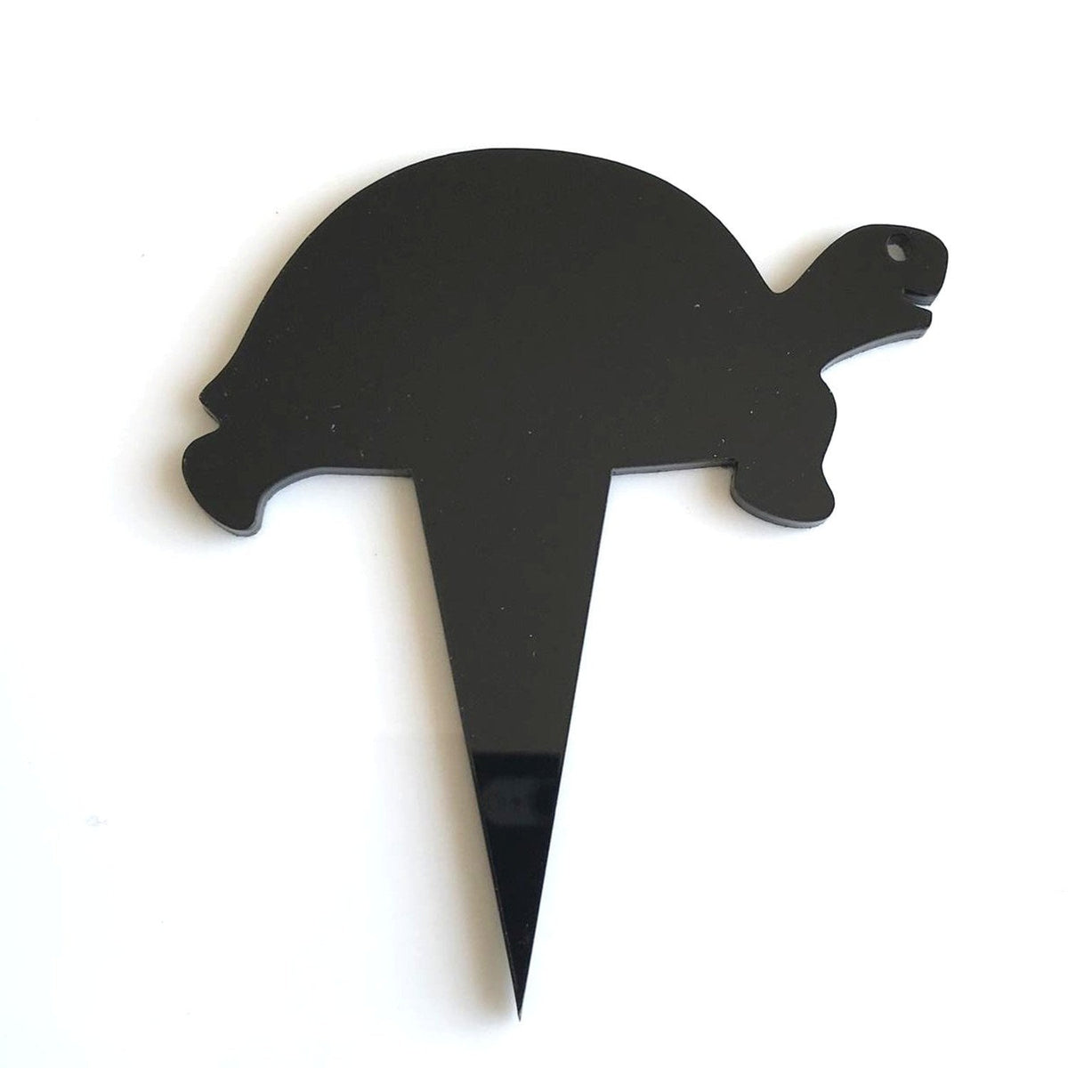 A shiny black acrylic turtle-shaped cupcake topper with a pointed stake for inserting into desserts.