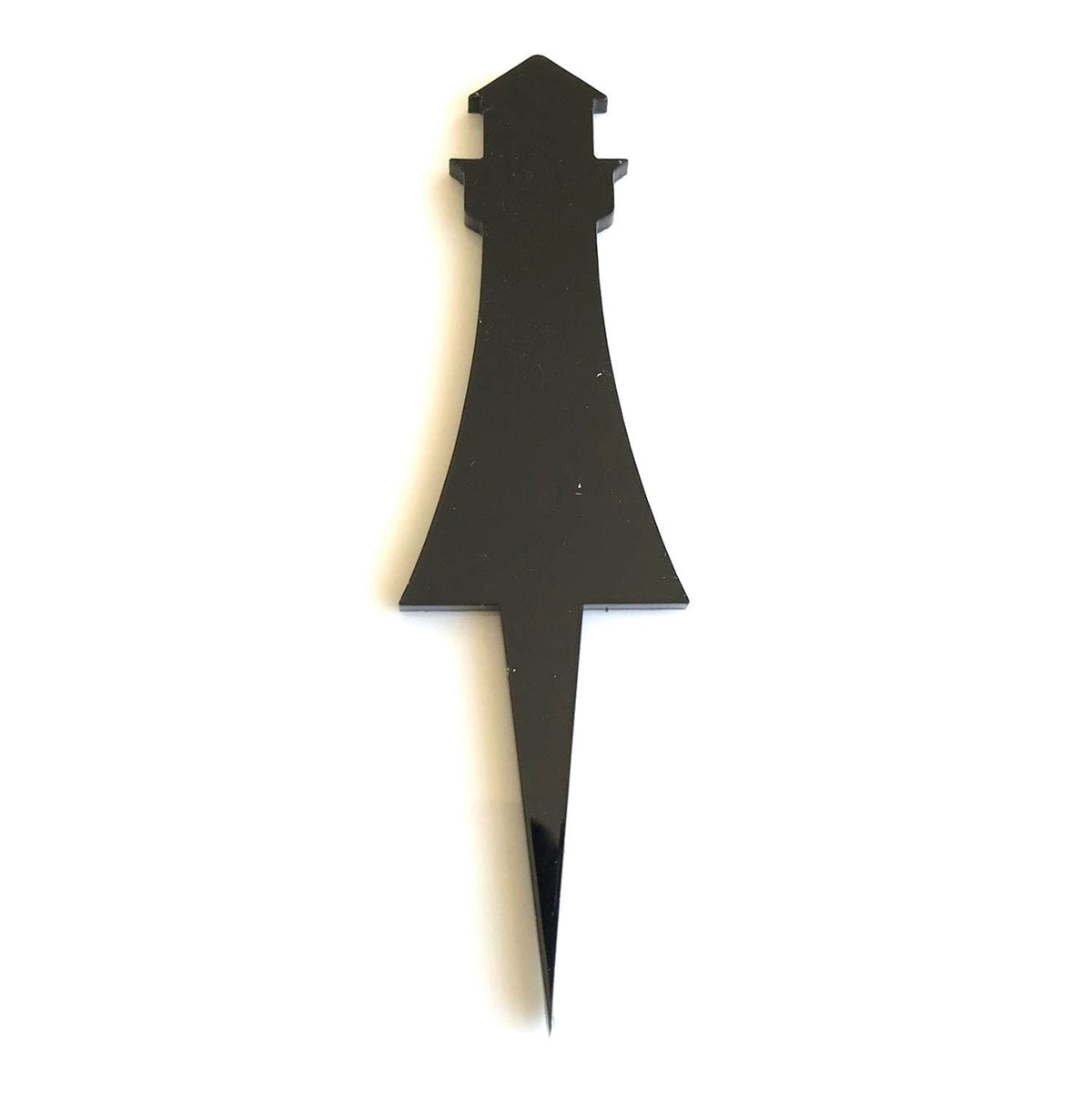 A solid black, glossy lighthouse-shaped cake topper with a sharp pointed stake base on a plain white background.