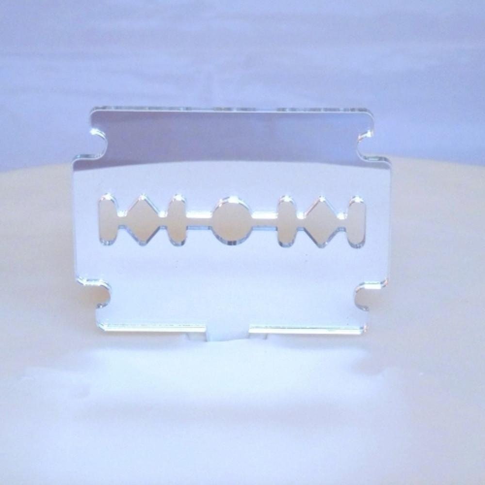 A reflective, silver-colored acrylic razor blade cake topper with a cutout center design.