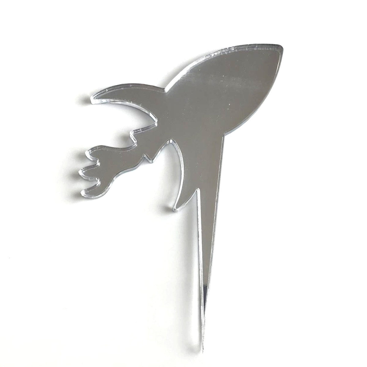Shiny silver mirror-finish acrylic rocket cake topper with a pointed stake for inserting into a cake.