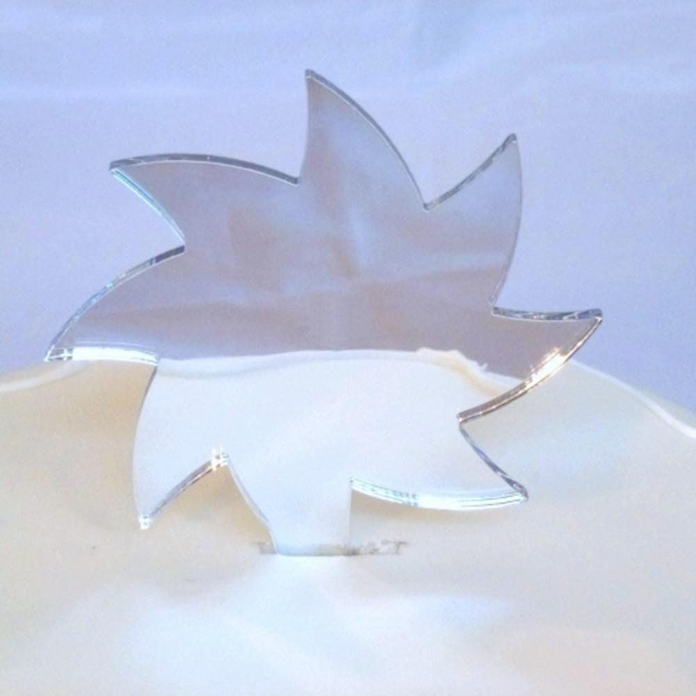 A reflective, silver-toned, spiral star-shaped cake topper made of recycled acrylic, resting on a white cake surface.