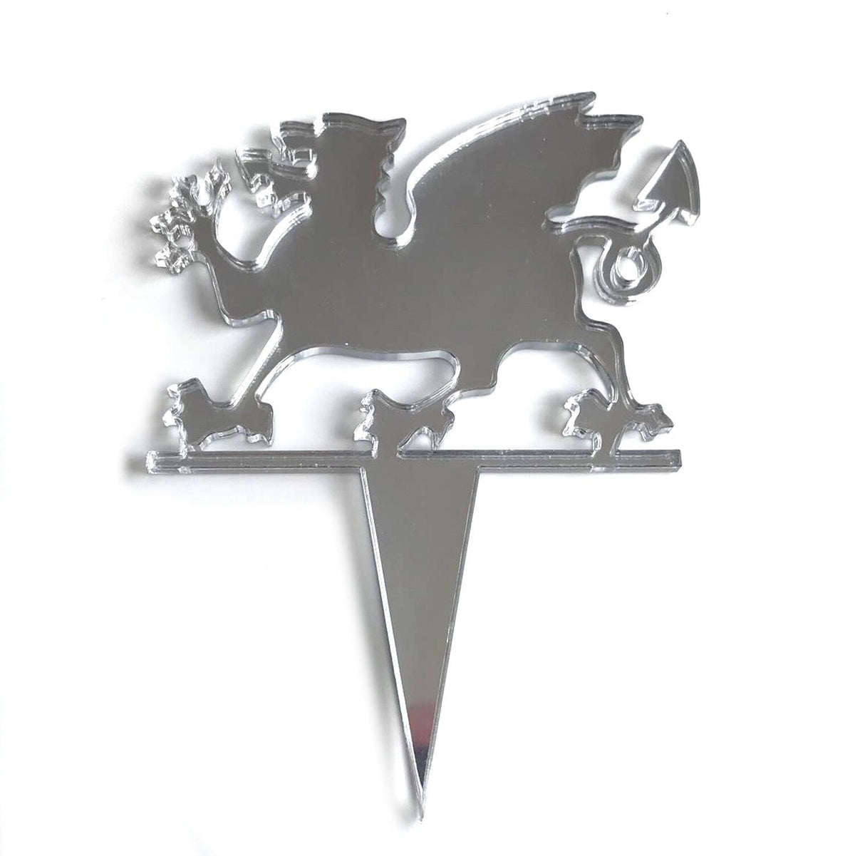 Reflective silver acrylic Welsh dragon cake topper with a sharp spike base on a plain white background.
