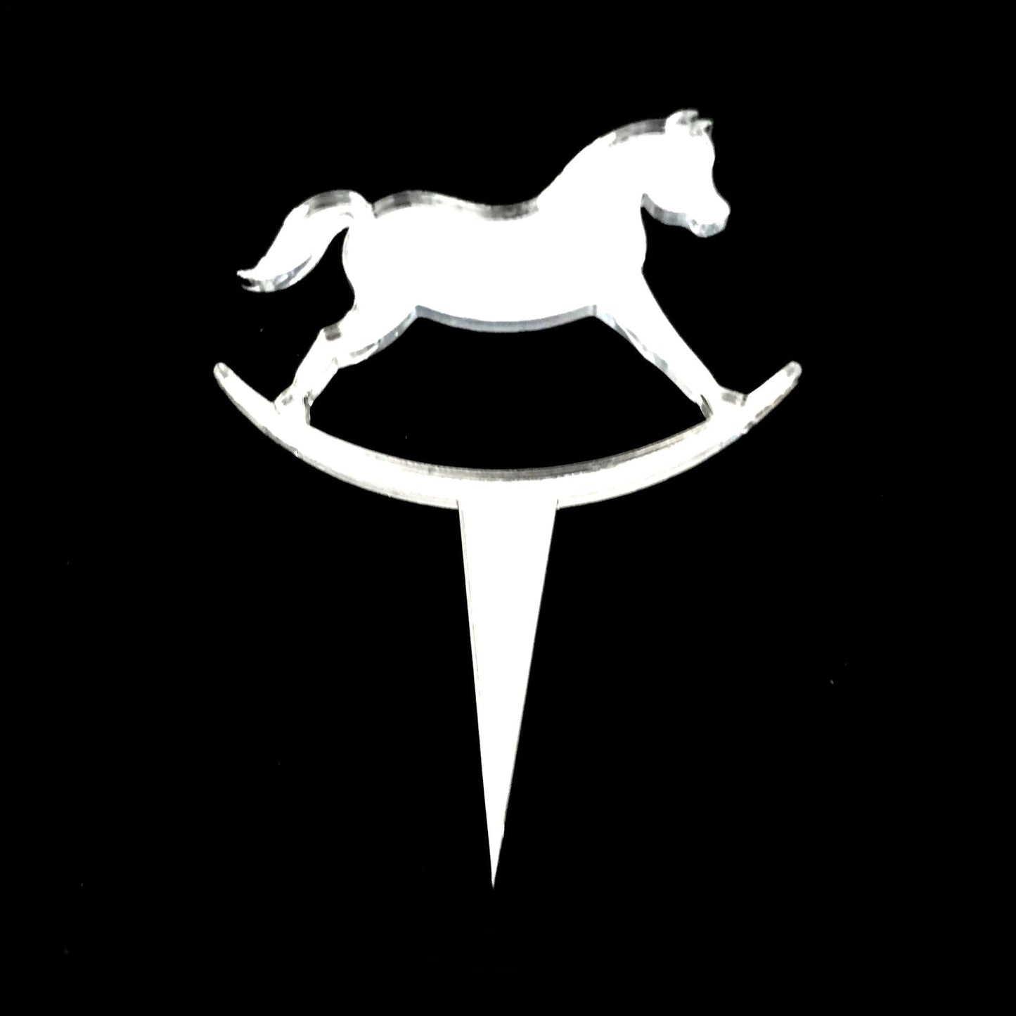 Clear acrylic rocking horse cake topper with a pointed stake for insertion, shown against a black background.