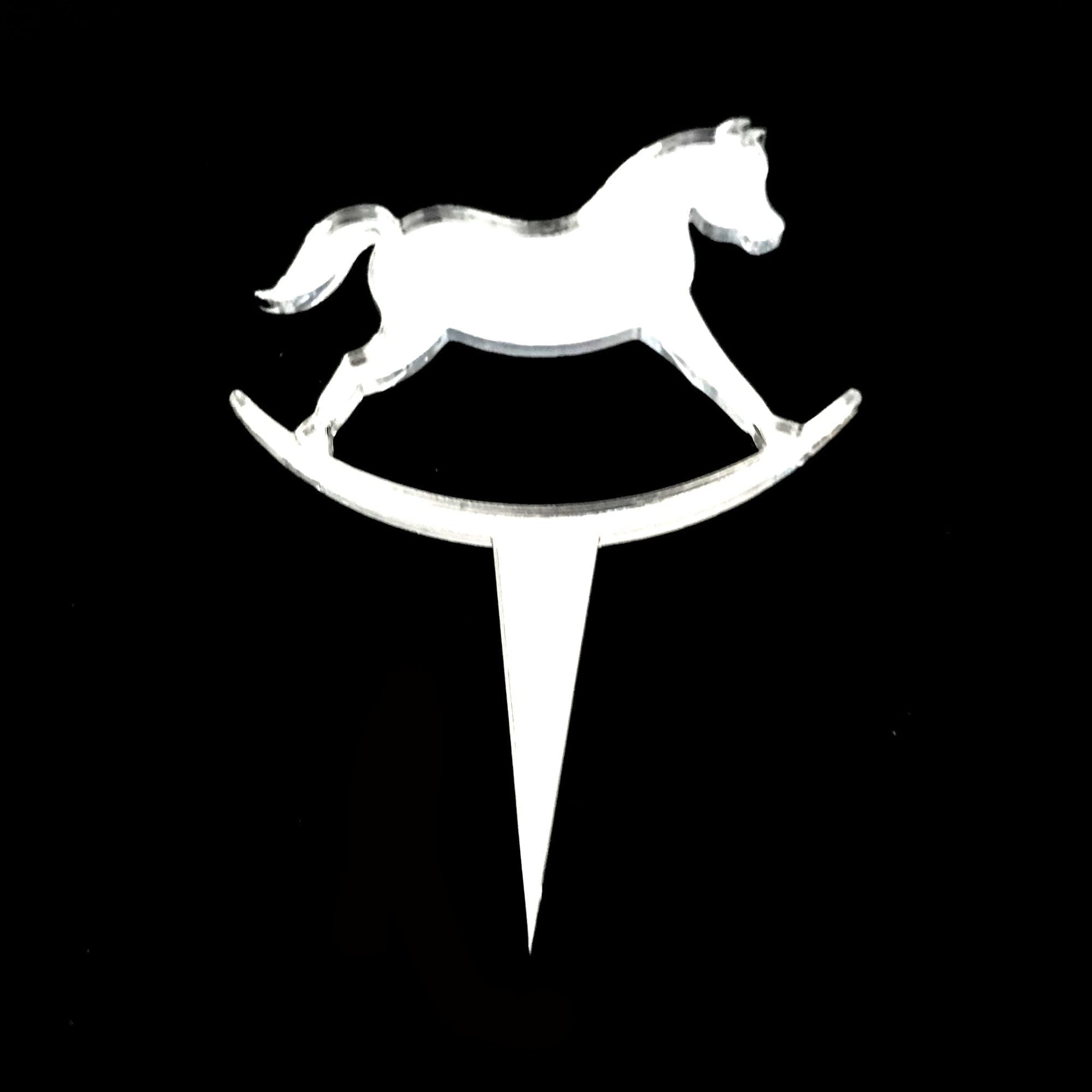 Clear acrylic rocking horse cake topper with a pointed stake for insertion, shown against a black background.