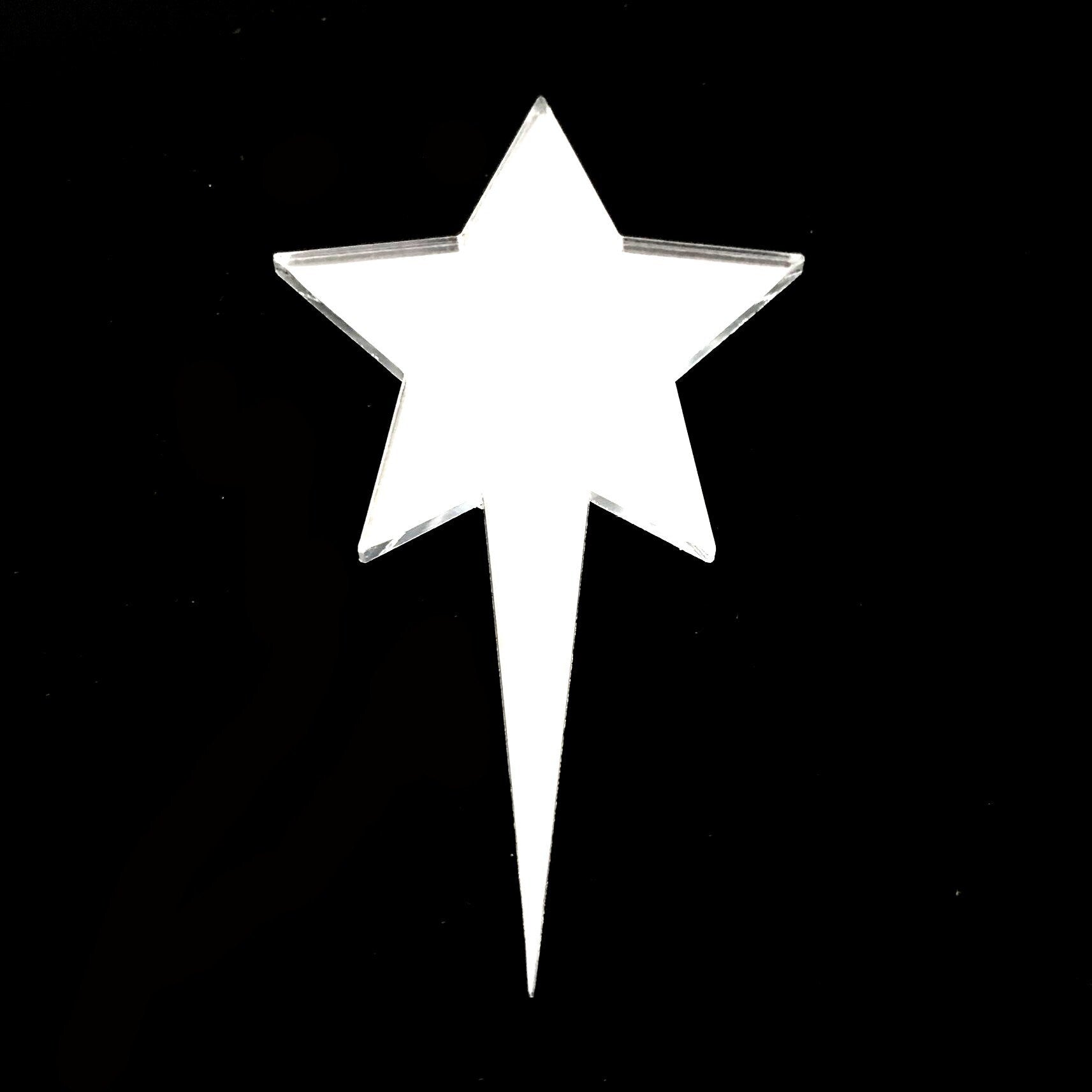 A shiny, reflective, silver-toned acrylic star cake topper with a sharp, pointed base against a black background.