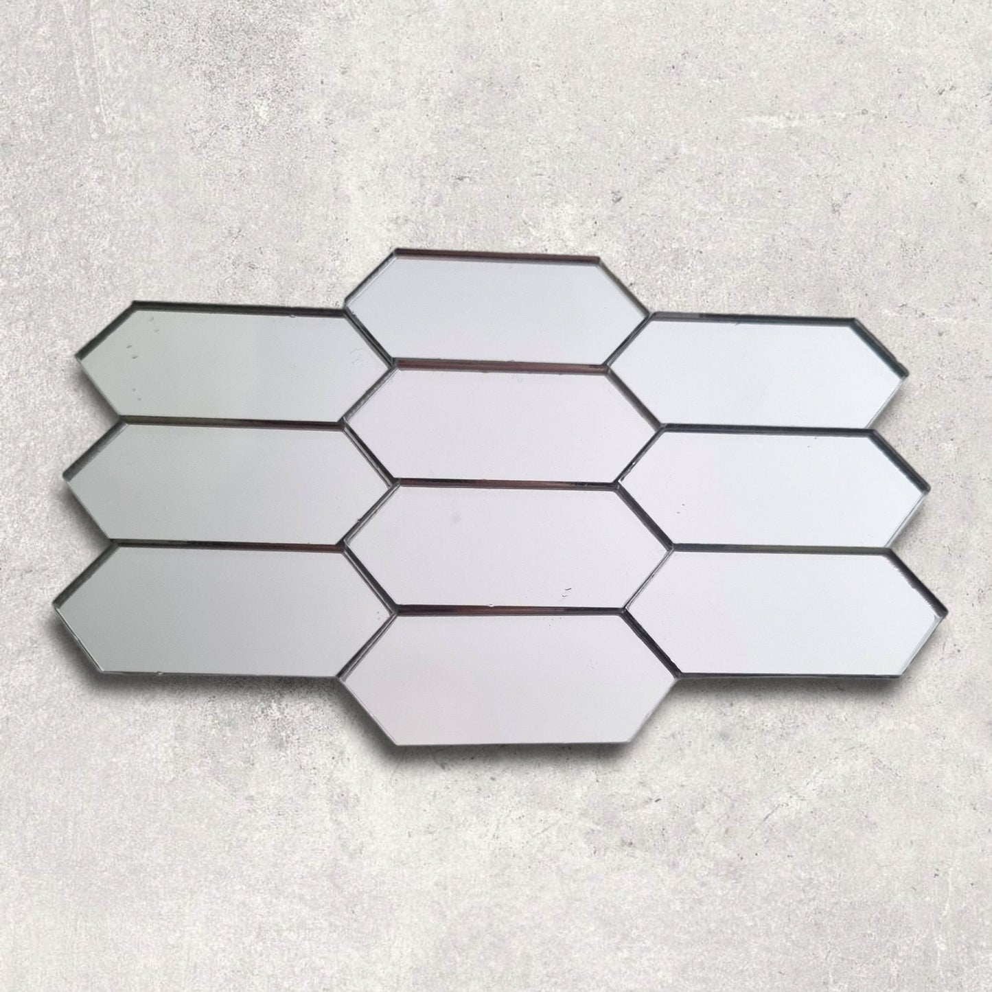 Silver elongated hexagon acrylic mirror tiles arranged in a mosaic pattern on a textured background.