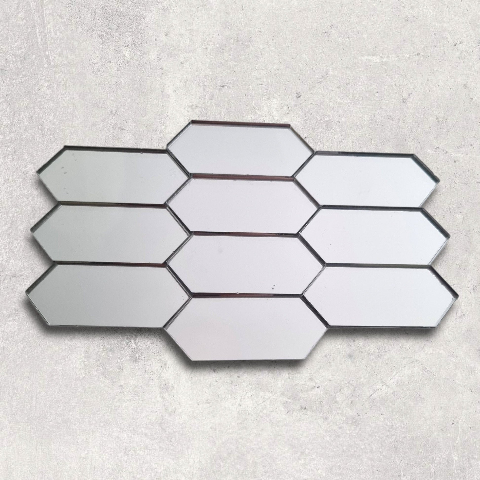Silver elongated hexagon acrylic mirror tiles arranged in a mosaic pattern on a textured background.