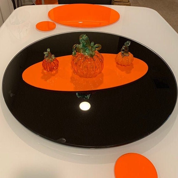 Oval black acrylic worktop saver with an orange oval accent, topped with three decorative glass pumpkins.