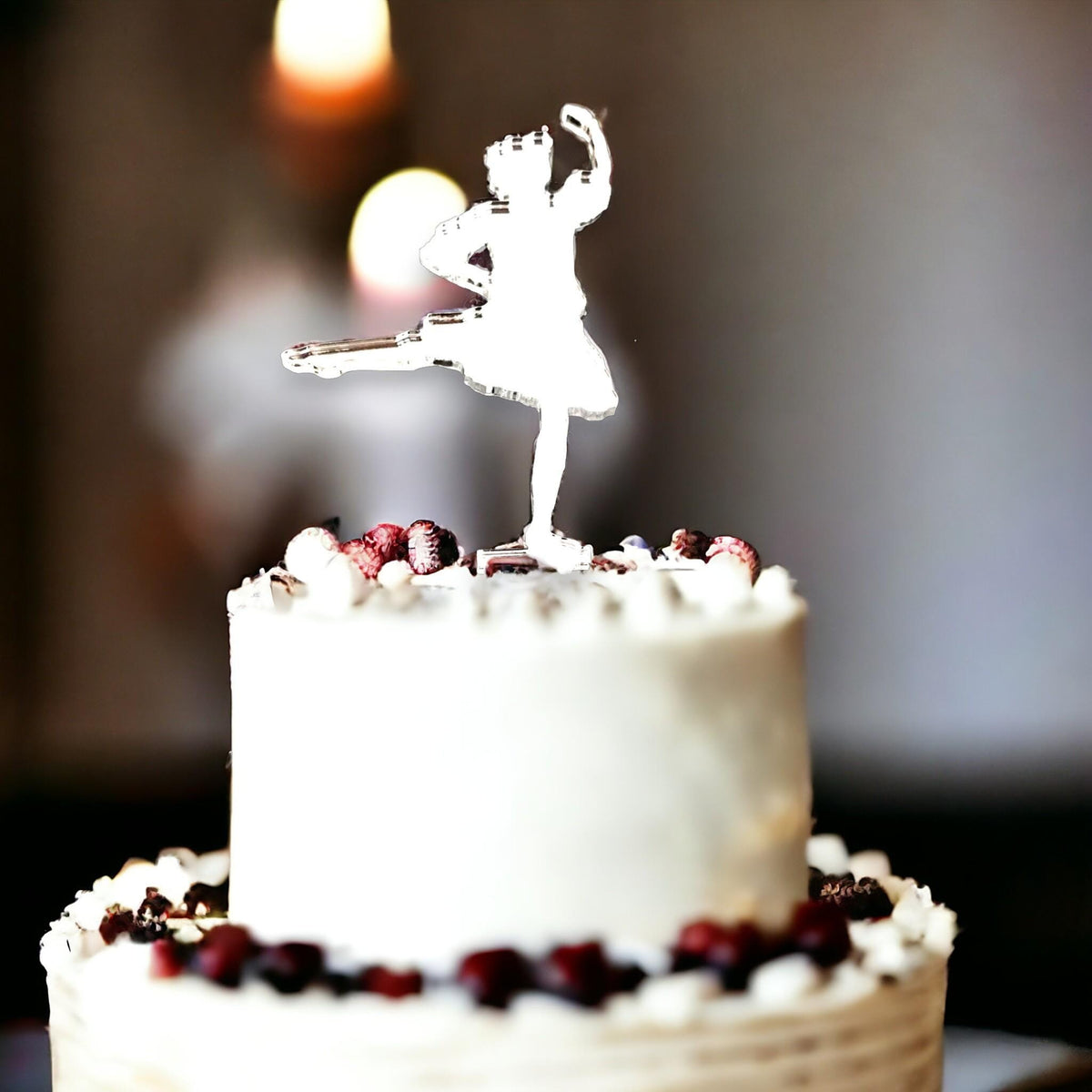 Clear acrylic Highland dancer cake topper silhouette on a white frosted cake with dark berries.