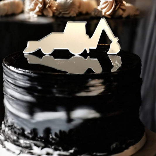 A mirrored silver digger-shaped cake topper sits on top of a smooth, glossy black cake.