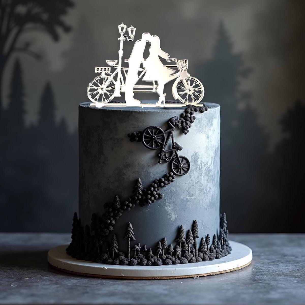 Clear acrylic bicycle cake topper featuring a couple kissing under a street lamp atop a grey forest-themed cake.