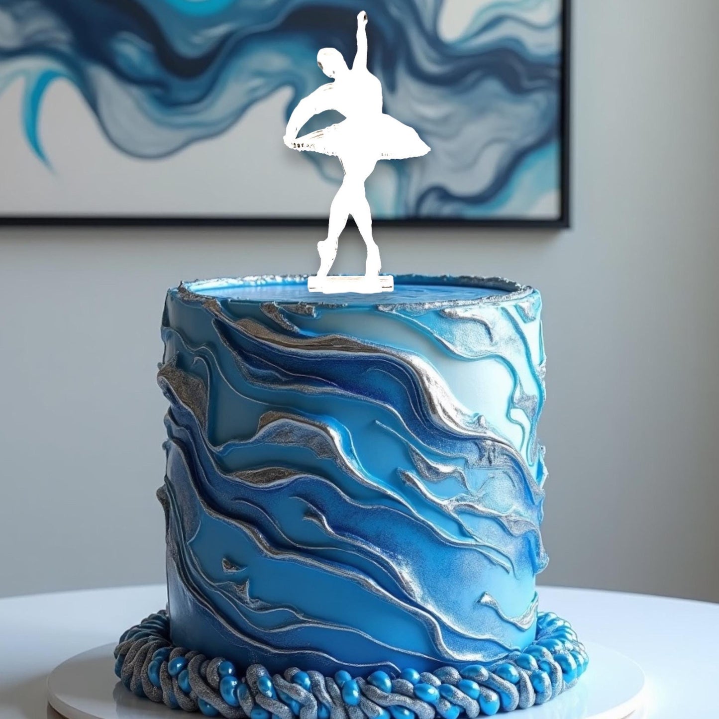 White silhouette ballerina cake topper by SuperCoolCreations atop a blue and silver marbled textured cake.