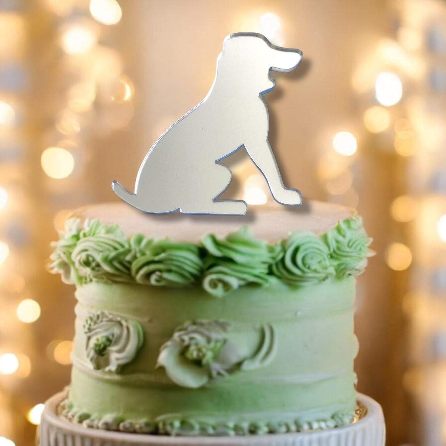 Reflective silver acrylic beagle dog silhouette cake topper sitting atop a frosted green cake.