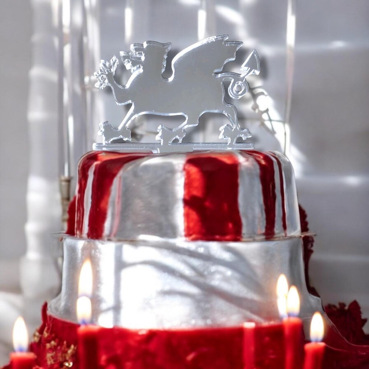 Shiny silver mirror-finish Welsh dragon acrylic cake topper atop a metallic red and silver tiered cake.