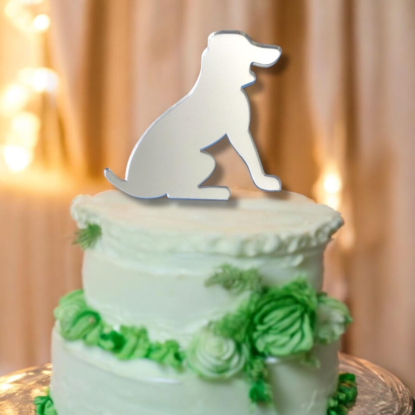 Silver mirrored acrylic beagle dog silhouette cake topper sitting on a two-tier white frosted cake with green florals.