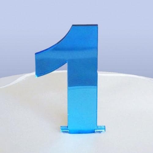 Shiny blue acrylic number 1 cake topper standing on a white cake surface.