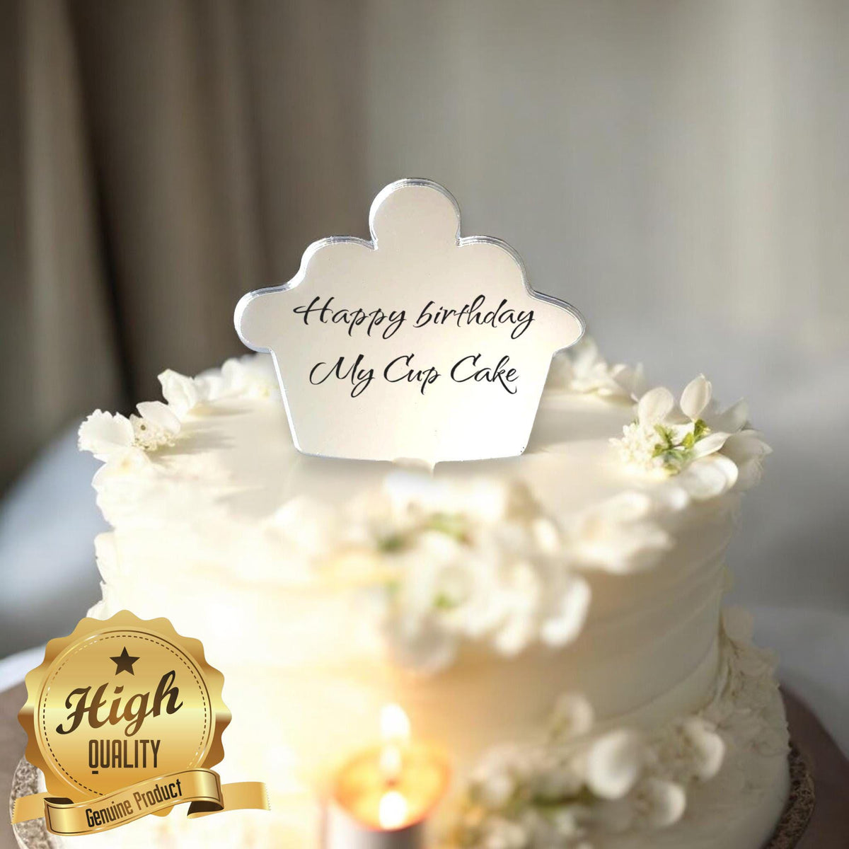 Mirror-finish cupcake-shaped cake topper with "Happy birthday My Cup Cake" in black script on a white floral cake.