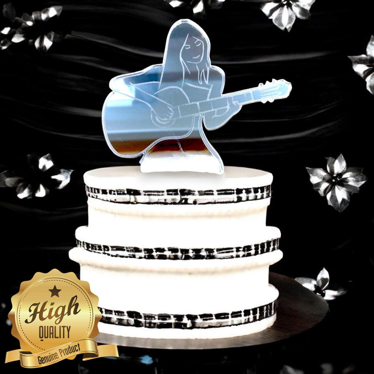 Mirrored acrylic cake topper of a woman playing an acoustic guitar, displayed on a white cake with music notes.