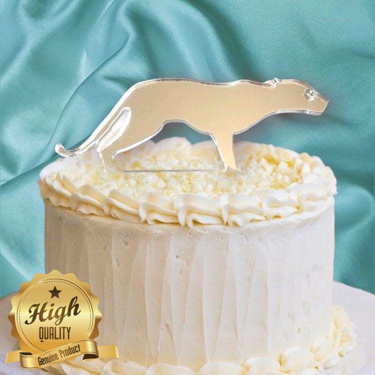 A silver mirror-finish acrylic jaguar silhouette cake topper resting on a white frosted cake.