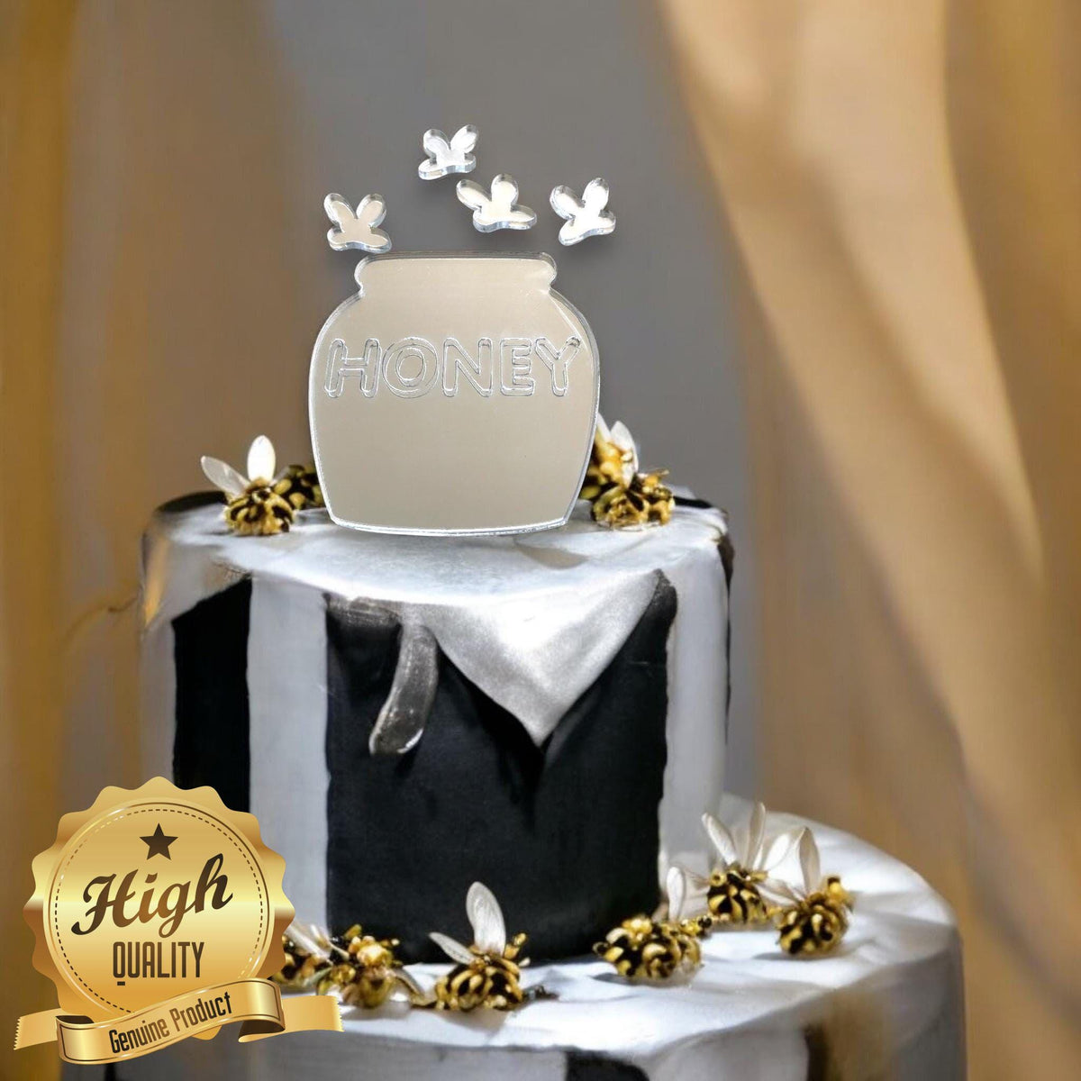 Mirrored acrylic honeypot cake topper engraved with "HONEY" and floating bee accents, on a black and white striped cake.