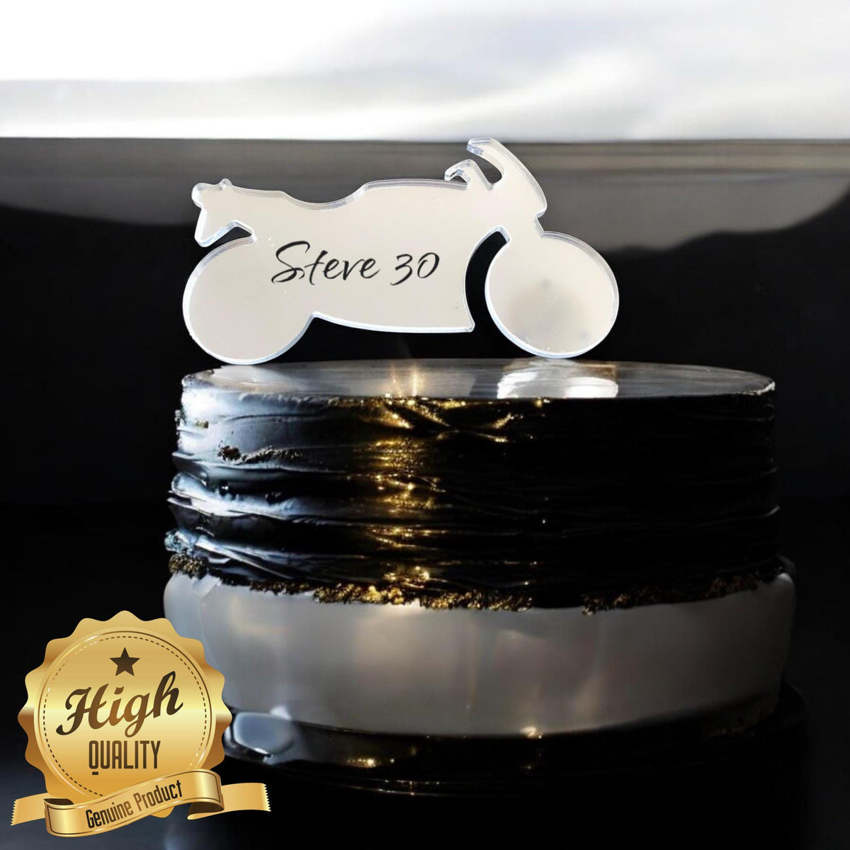 Clear acrylic motorbike cake topper personalized with "Steve 30" in black script, atop a textured black cake.