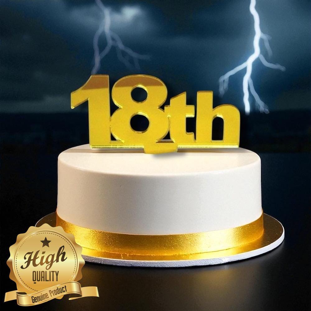 Shiny gold "18th" acrylic cake topper centered on a round white cake with a gold ribbon border.