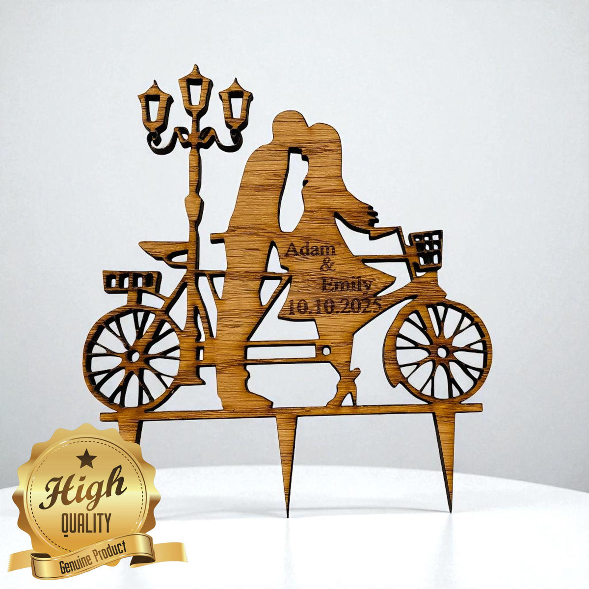 Laser-cut wood cake topper of a couple on a bicycle with a streetlamp, personalized with "Adam & Emily 10.10.2025".