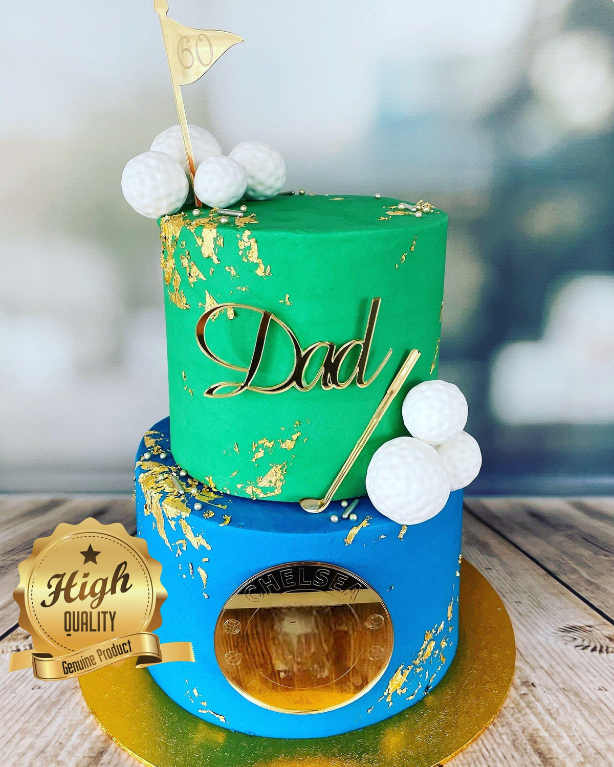 Gold acrylic "Dad" cake topper, a golf flag with "60", and a Chelsea emblem on a two-tier green and blue golf cake.
