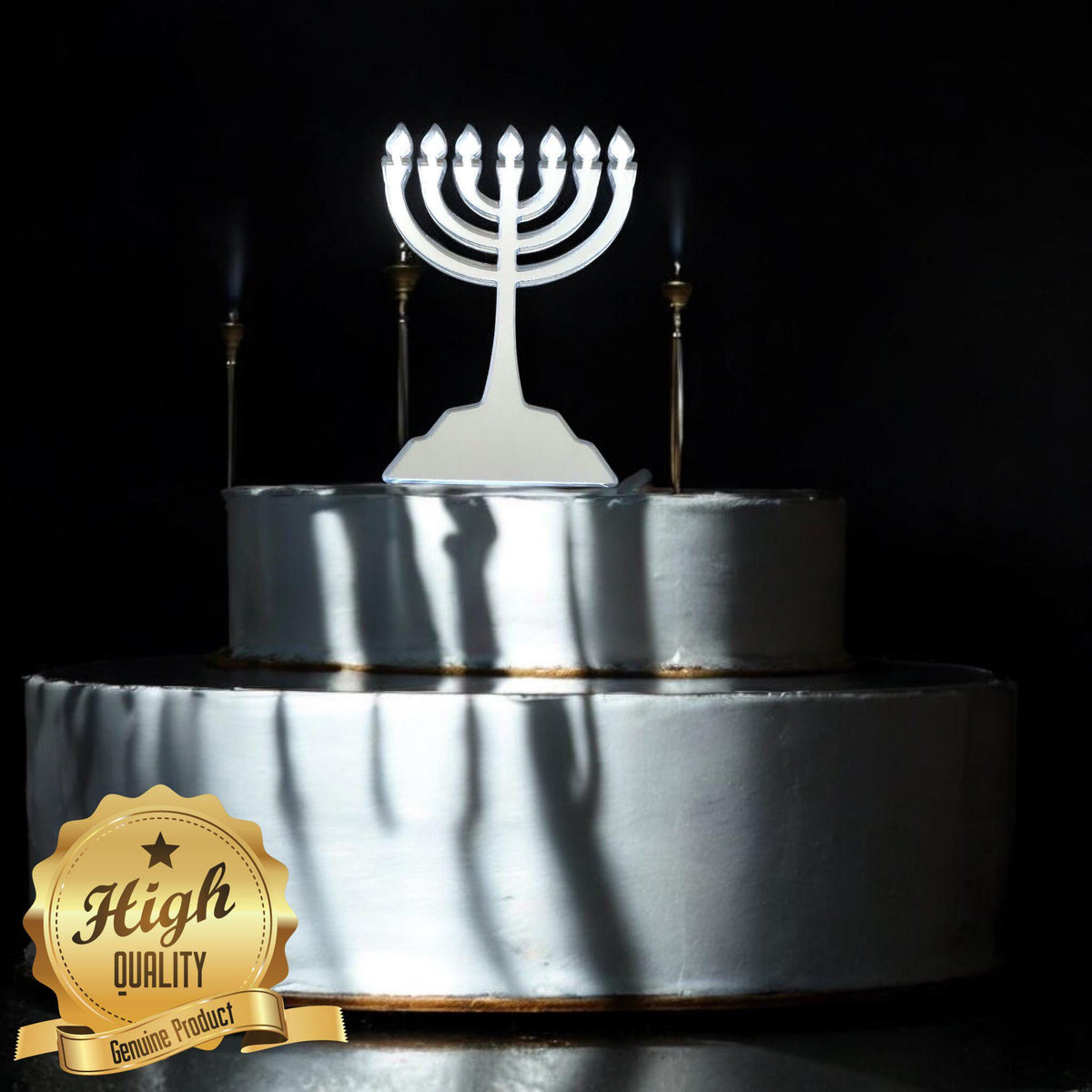 Shiny silver acrylic menorah cake topper on a two-tier white cake against a black background.