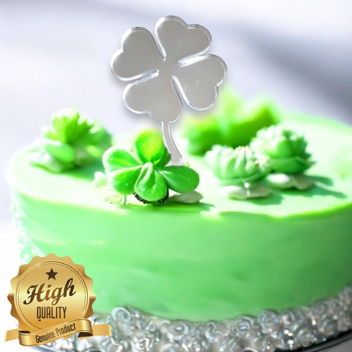 Shiny, silver, mirror-finish acrylic four-leaf clover cake topper inserted into a green frosted cake.