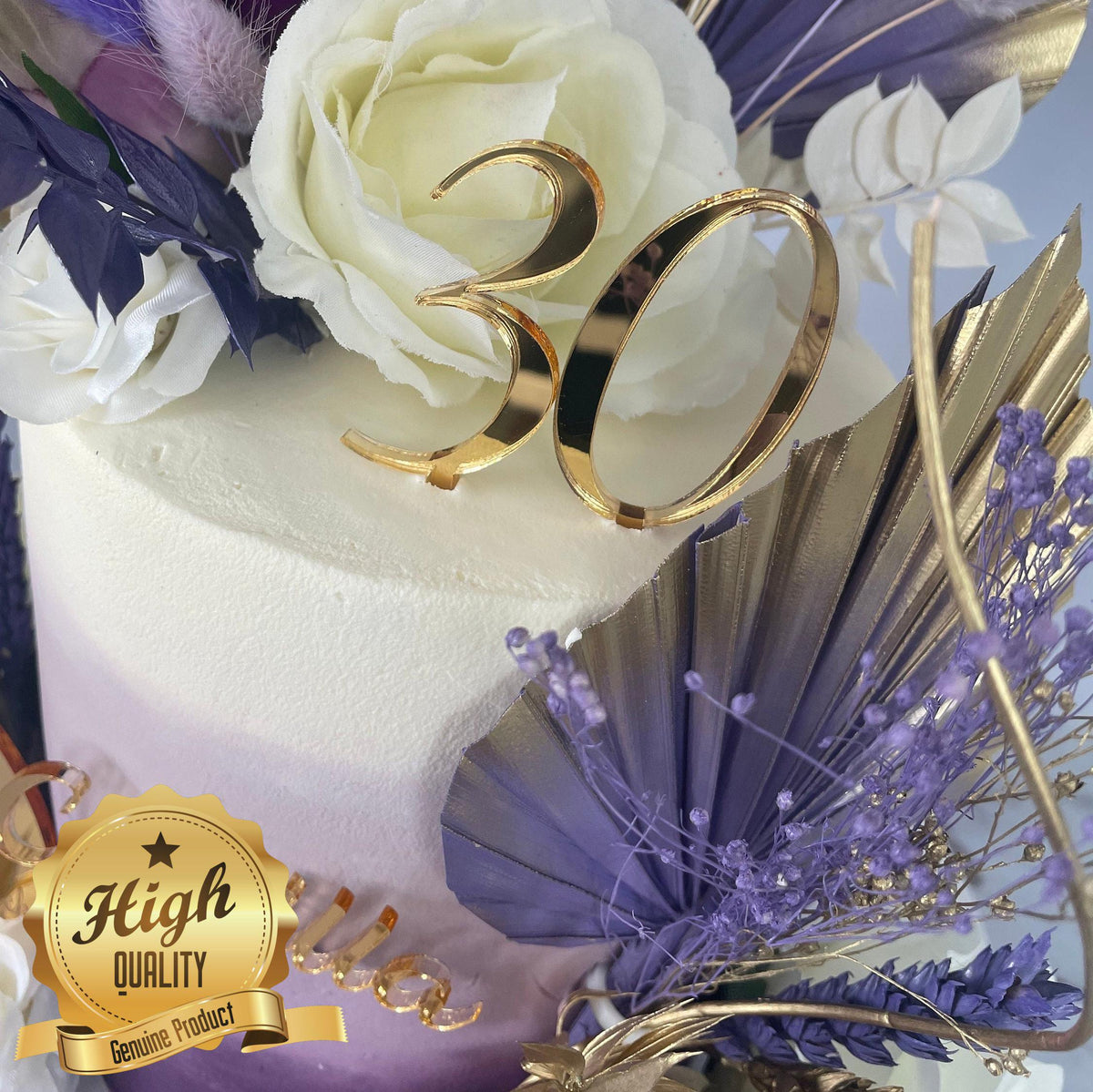 Gold mirrored acrylic "30" cake topper on a white cake decorated with purple and gold dried floral accents.