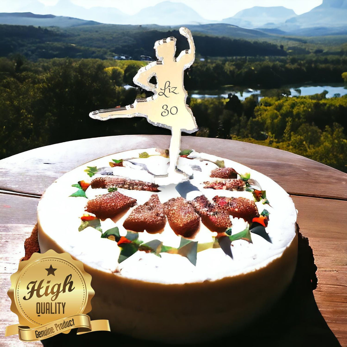 Gold mirror acrylic Highland dancer cake topper with "Liz 30" text on a cake, set against a mountain landscape.