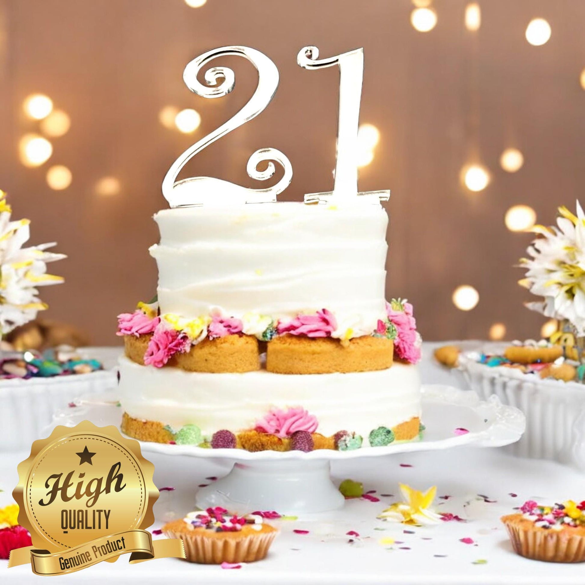 A shiny, silver-mirrored acrylic number "21" cake topper in an elegant cursive font, placed atop a two-tier cake.