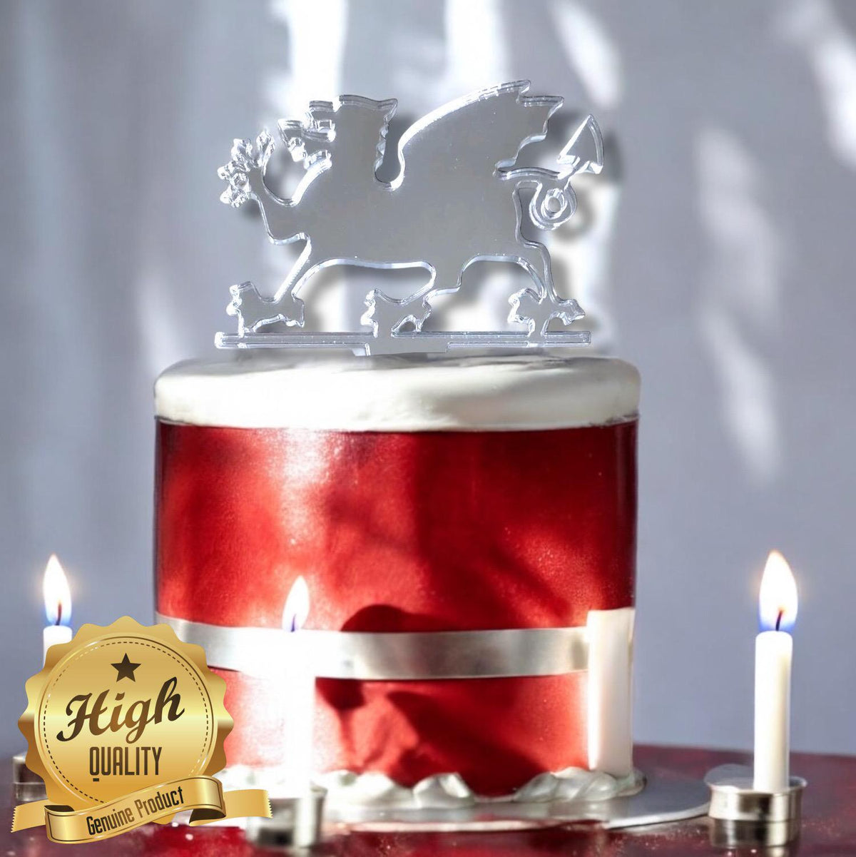 Silver mirror acrylic Welsh Dragon cake topper on a red birthday cake with candles and a High Quality badge.