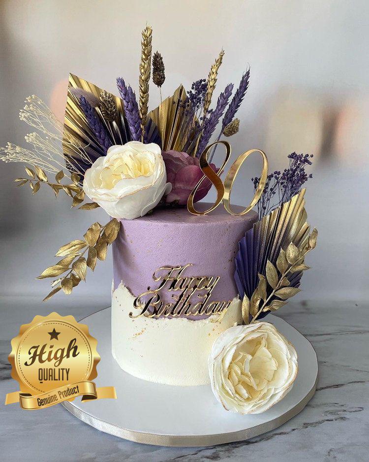 Gold laser-cut "80" and "Happy Birthday" acrylic cake toppers on a decorated purple and white cake.