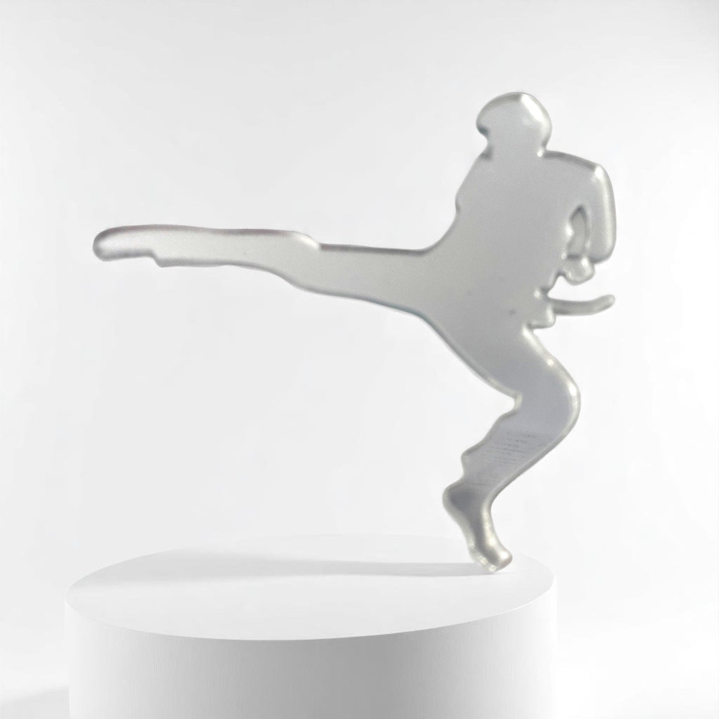 Silver martial arts man-shaped mirror standing upright on a white cylindrical display podium.