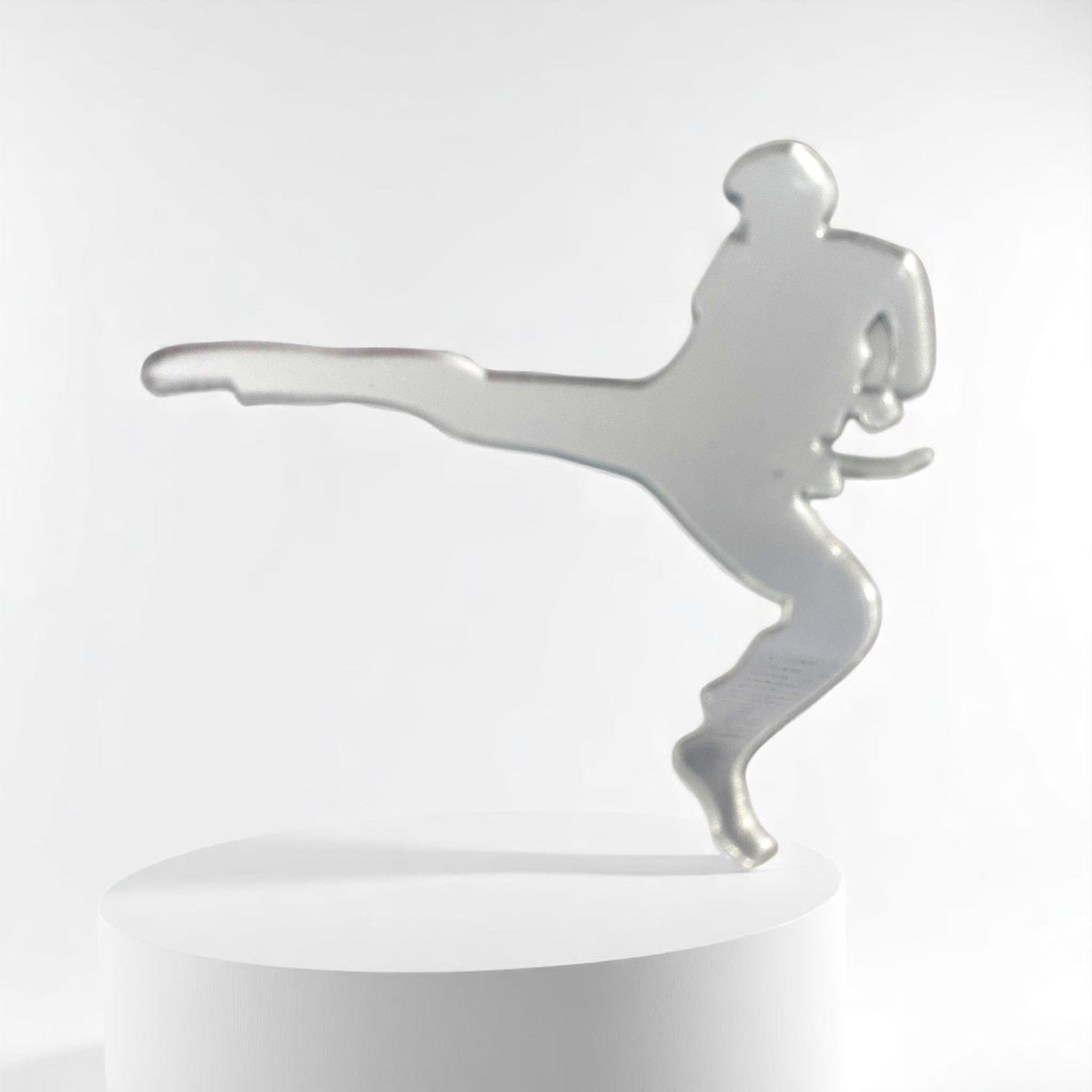 Silver martial arts man-shaped mirror standing upright on a white cylindrical display podium.
