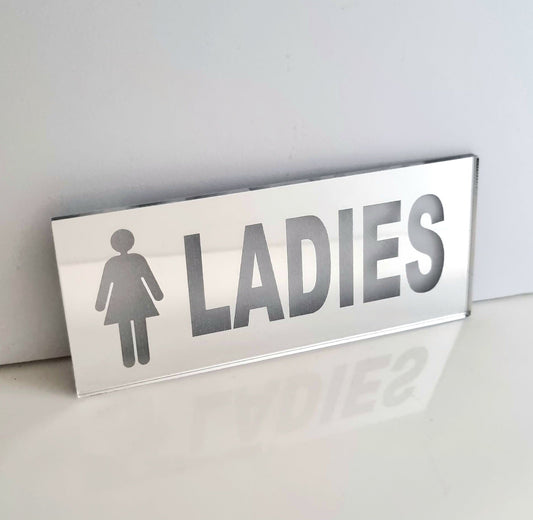 Rectangular mirrored acrylic ladies toilet sign with a female symbol and the word LADIES.