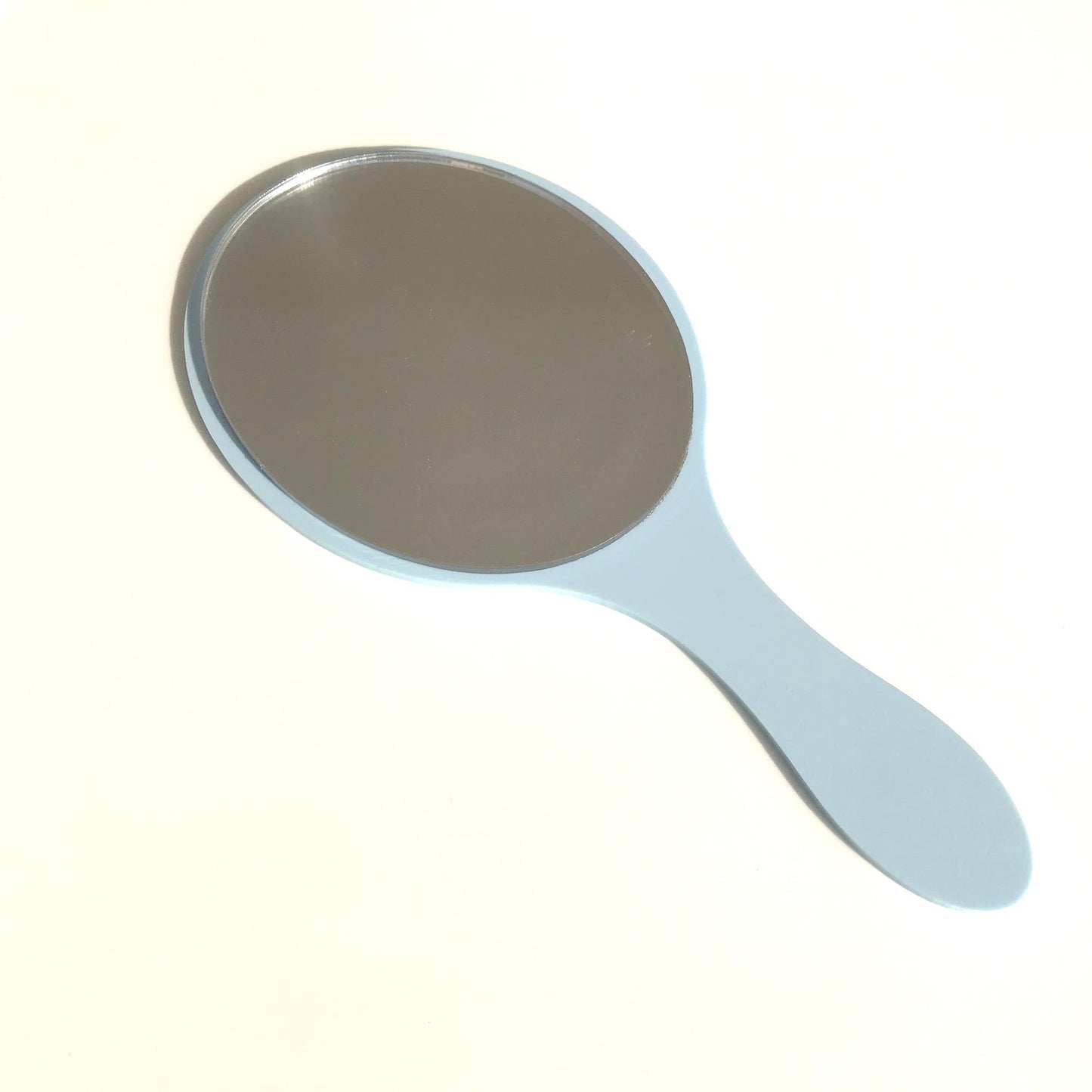 Oval hand-held mirror with a light blue gloss handle on a white surface.
