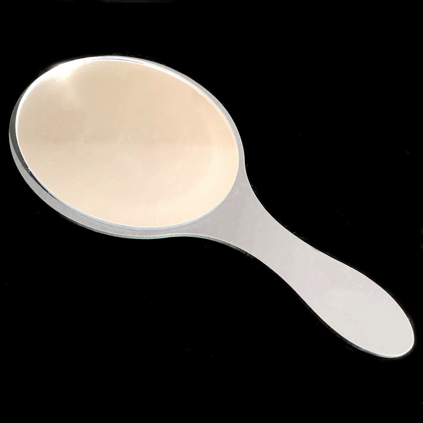 An oval hand-held mirror with a glossy white handle against a black background.