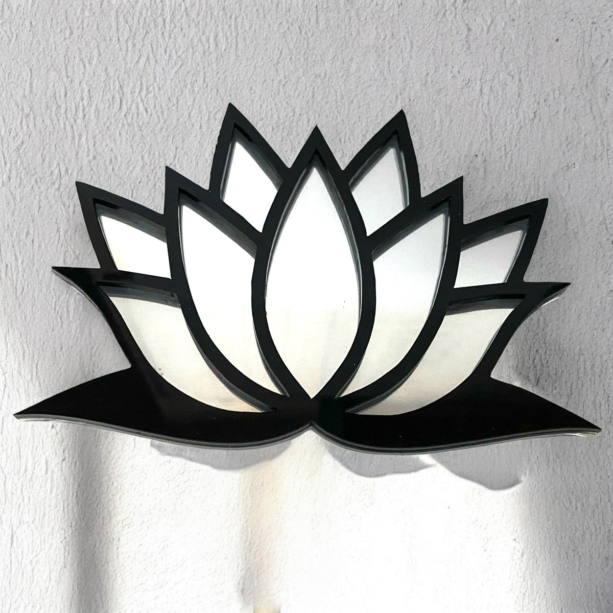 Black-framed lotus flower garden mirror mounted on a textured white wall.